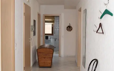 Flur der Ferienwohnung mit Garderobe, alter Holztruhe und Blick ins Bad
