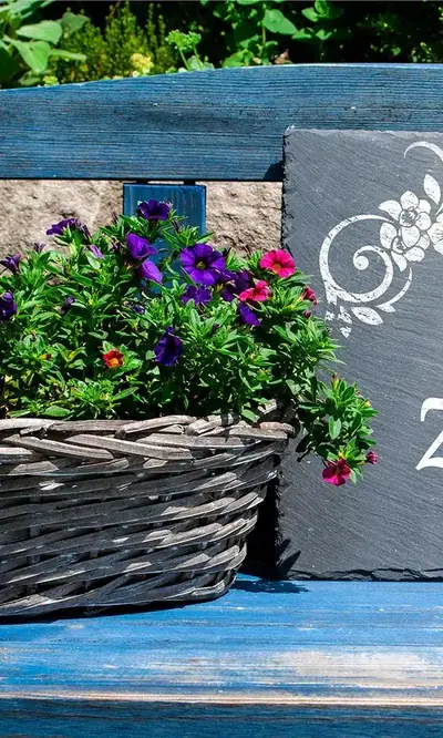 Blumenkorb auf einer blauen Holzbank im Garten