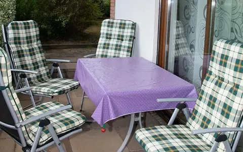 Überdachte Terrasse mit Gartentisch und vier gepolsterten Klappstühlen